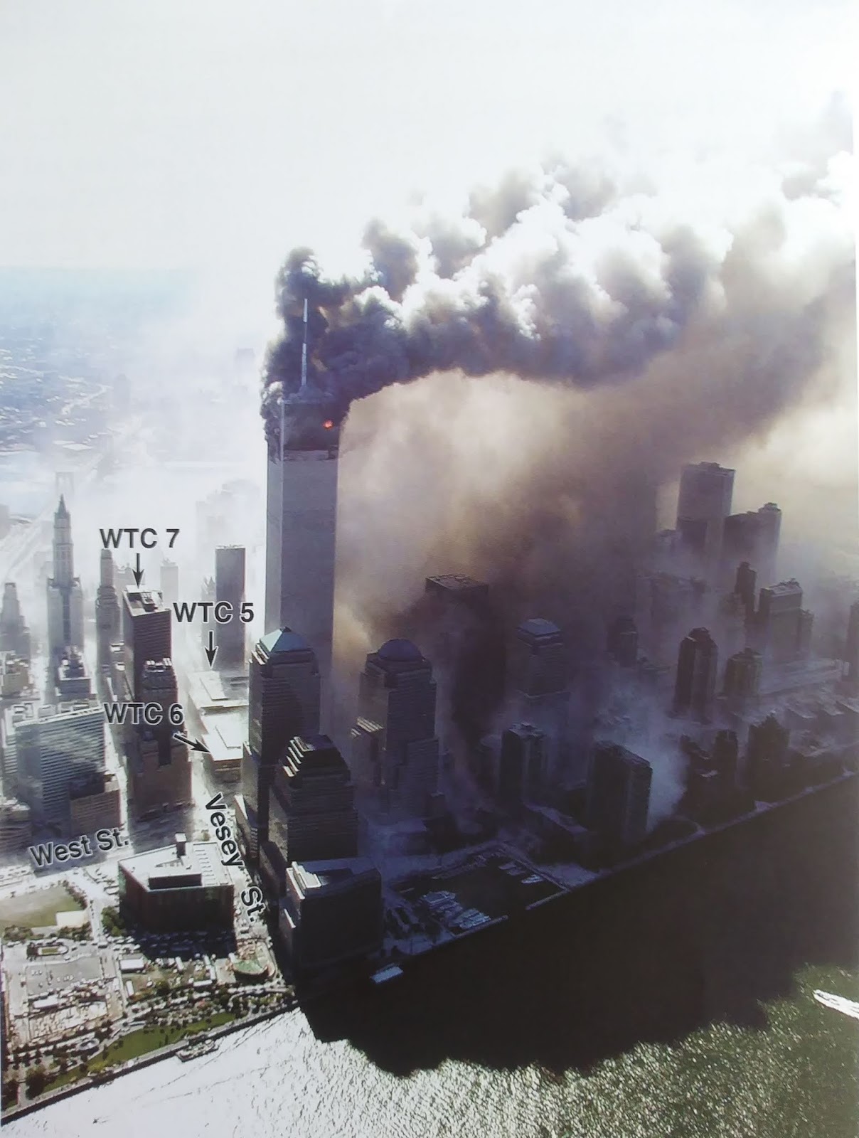 Aerial view showing distinct coloration in clouds with dense dark fumes from WTC1 and lighter white dust from WTC2, demonstrating heterogeneous aerosol separation